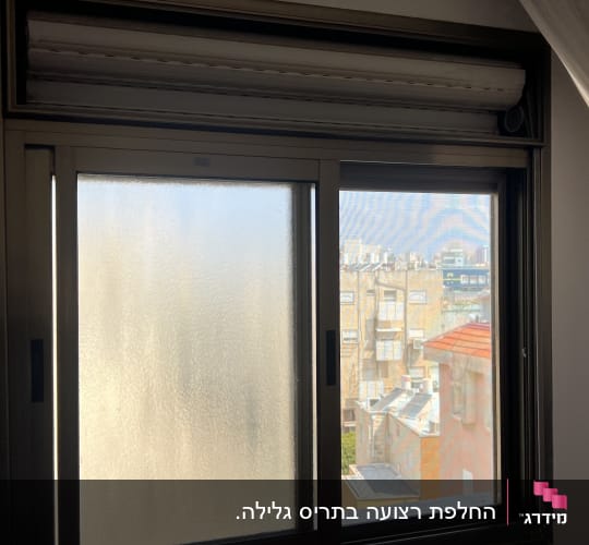 חלון עם תריסים סגורים ונוף עירוני ברקע